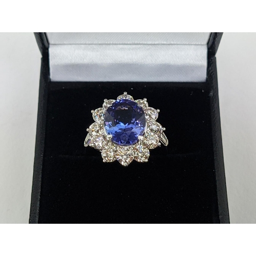 32 - AN 18CT WHITE GOLD TANZANITE AND DIAMOND CLUSTER RING, the central mixed cut stone of 4.95 carats, s... 