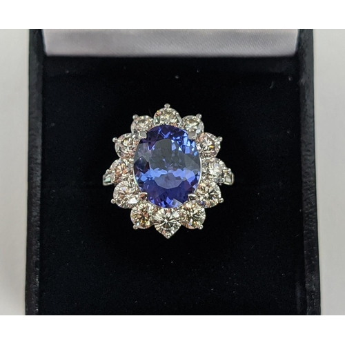 32 - AN 18CT WHITE GOLD TANZANITE AND DIAMOND CLUSTER RING, the central mixed cut stone of 4.95 carats, s... 