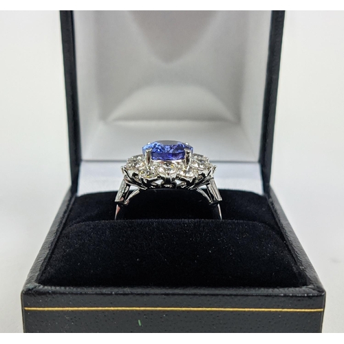 32 - AN 18CT WHITE GOLD TANZANITE AND DIAMOND CLUSTER RING, the central mixed cut stone of 4.95 carats, s... 