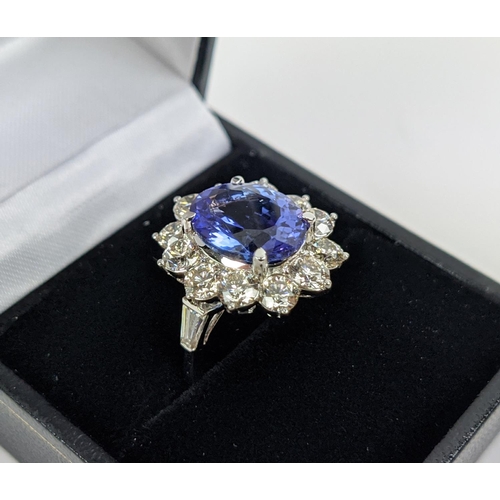 32 - AN 18CT WHITE GOLD TANZANITE AND DIAMOND CLUSTER RING, the central mixed cut stone of 4.95 carats, s... 