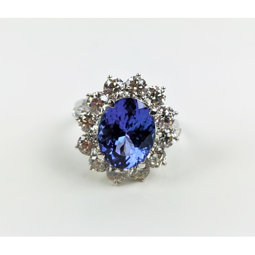 32 - AN 18CT WHITE GOLD TANZANITE AND DIAMOND CLUSTER RING, the central mixed cut stone of 4.95 carats, s... 