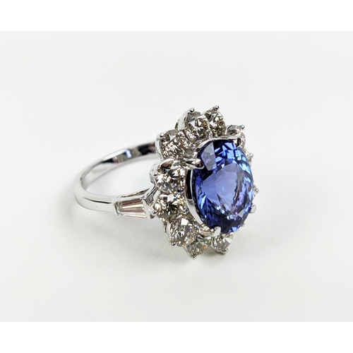 32 - AN 18CT WHITE GOLD TANZANITE AND DIAMOND CLUSTER RING, the central mixed cut stone of 4.95 carats, s... 