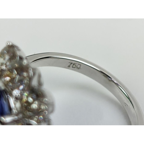 32 - AN 18CT WHITE GOLD TANZANITE AND DIAMOND CLUSTER RING, the central mixed cut stone of 4.95 carats, s... 