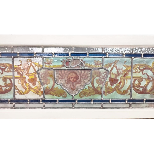 182 - STAINED GLASS PANEL, mask and foliate scroll design in painted frame, 35cm H x 91cm.