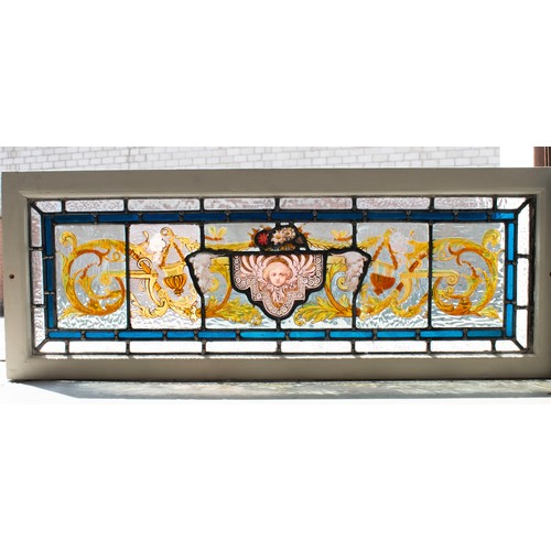 182 - STAINED GLASS PANEL, mask and foliate scroll design in painted frame, 35cm H x 91cm.