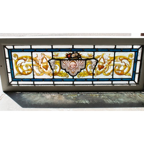 182 - STAINED GLASS PANEL, mask and foliate scroll design in painted frame, 35cm H x 91cm.