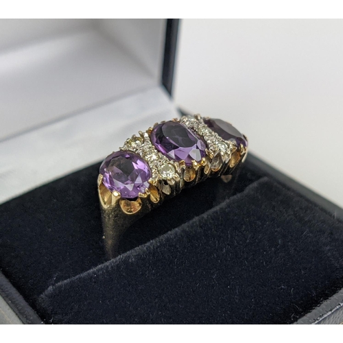 18 - A 9CT GOLD AMETHYST AND DIAMOND DRESS RING, set with three mixed cut amethysts with diamond set spac... 