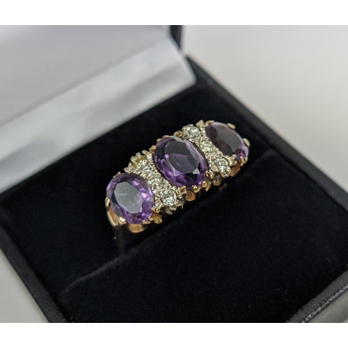 18 - A 9CT GOLD AMETHYST AND DIAMOND DRESS RING, set with three mixed cut amethysts with diamond set spac... 