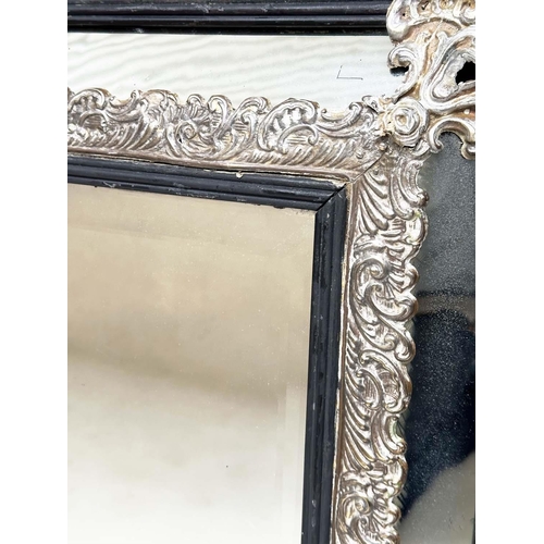 249 - WALL MIRROR, 19th century Flemish repoussé silvered metal and ebonised with cushion and bevelled mar... 