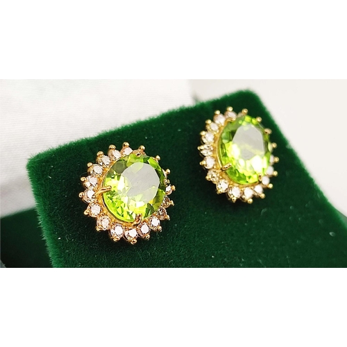 146 - A PAIR OF 18CT GOLD PERIDOT AND DIAMOND STUD EARRINGS, each with a oval mixed cut peridot
of approxi... 