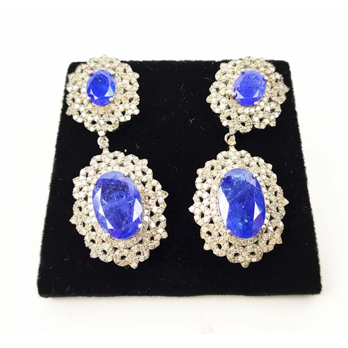 153 - A PAIR OF EDWARDIAN STYLE TANZANITE AND DIAMOND SET DROP EARRINGS, set with four oval
facet cut tanz... 