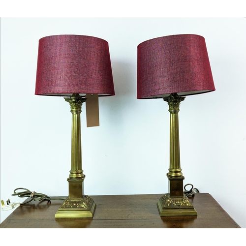 144 - LAMPS, a pair, Corinthian brass columns with red shades, 62cm H. (2)