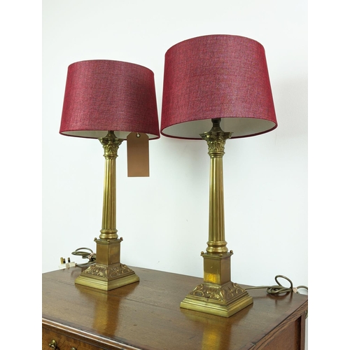 144 - LAMPS, a pair, Corinthian brass columns with red shades, 62cm H. (2)