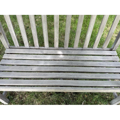 124 - GARDEN BENCH, well weathered slatted teak with shaped arms, 89cm H x 120cm W.