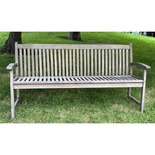 129 - GARDEN BENCH, weathered teak of slatted construction with slightly arch shaped back and curved arms,... 