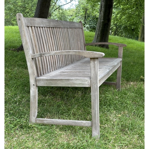 129 - GARDEN BENCH, weathered teak of slatted construction with slightly arch shaped back and curved arms,... 