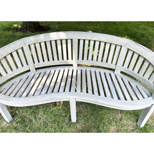 271 - BANANA GARDEN BENCH, well weathered teak of slatted construction with rounded back and arms, 158cm W... 