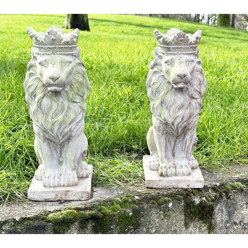 329 - GARDEN LIONS, a pair, weathered composite stone each seated and crowned, 35cm H. (2)