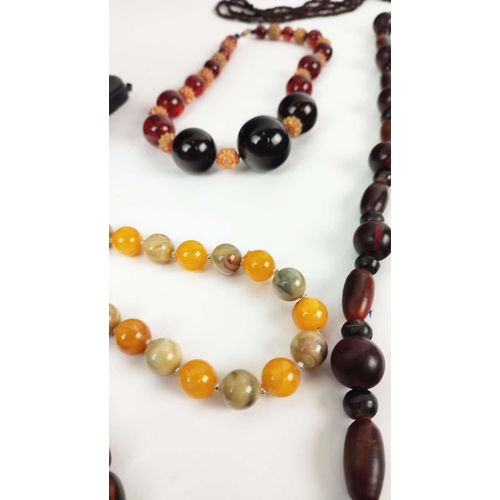 12 - A QUANTITY OF ASSORTED AMBER COLOURED BEAD NECKLACES, some glass and some in plastic, in red and ora... 