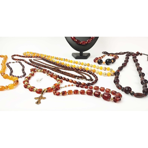 12 - A QUANTITY OF ASSORTED AMBER COLOURED BEAD NECKLACES, some glass and some in plastic, in red and ora... 