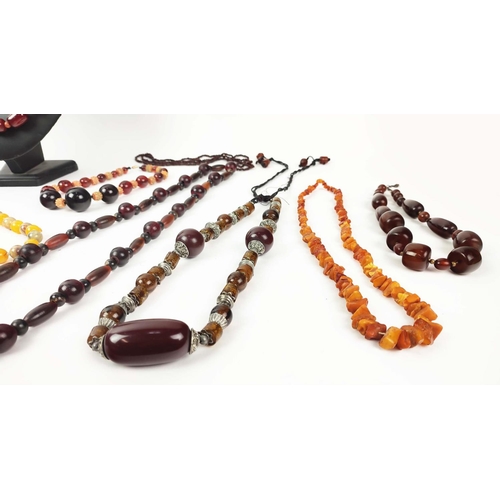 12 - A QUANTITY OF ASSORTED AMBER COLOURED BEAD NECKLACES, some glass and some in plastic, in red and ora... 