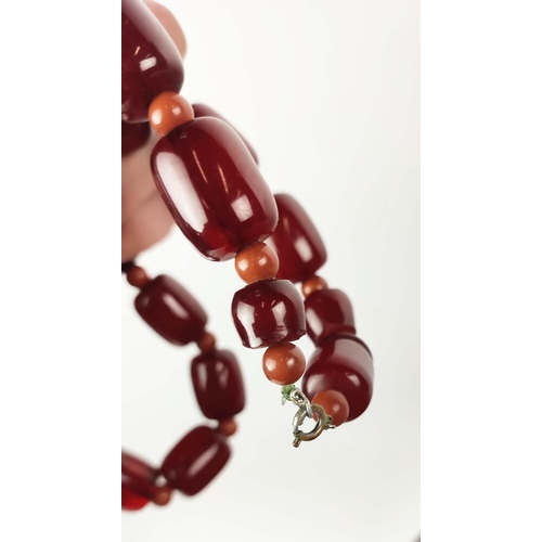 12 - A QUANTITY OF ASSORTED AMBER COLOURED BEAD NECKLACES, some glass and some in plastic, in red and ora... 