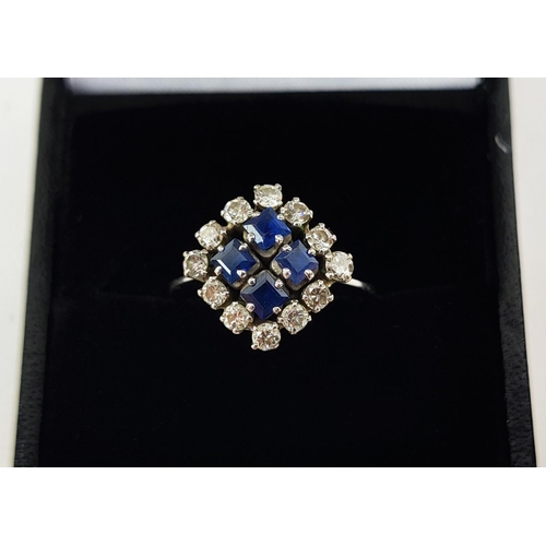 23 - A WHITE METAL DIAMOND AND SAPPHIRE SQUARE SET CLUSTER RING, with four sapphires surrounded by a halo... 