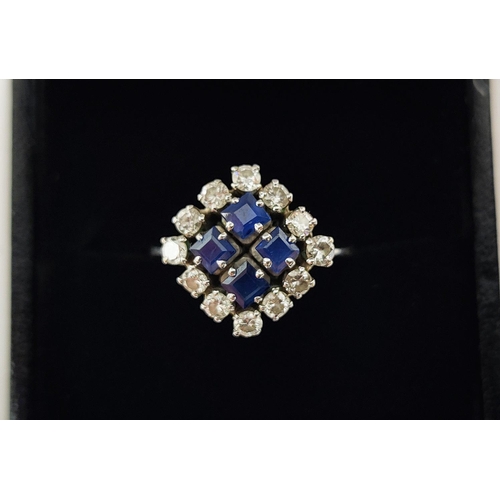 23 - A WHITE METAL DIAMOND AND SAPPHIRE SQUARE SET CLUSTER RING, with four sapphires surrounded by a halo... 