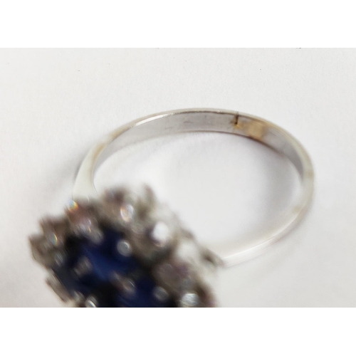 23 - A WHITE METAL DIAMOND AND SAPPHIRE SQUARE SET CLUSTER RING, with four sapphires surrounded by a halo... 