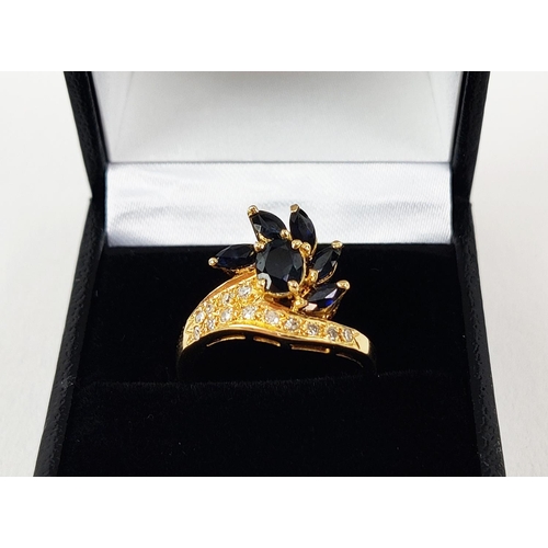 24 - A YELLOW METAL SAPPHIRE AND DIAMOND SET DRESS RING, probably 18ct gold, asymmetrical floral spray wi... 