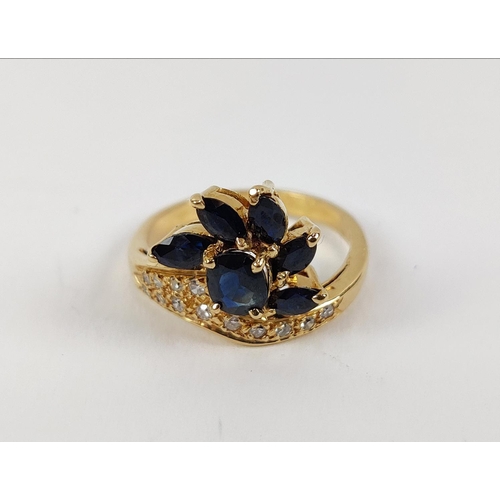 24 - A YELLOW METAL SAPPHIRE AND DIAMOND SET DRESS RING, probably 18ct gold, asymmetrical floral spray wi... 