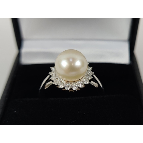 26 - A 9CT WHITE GOLD CULTURED PEARL AND DIAMOND RING, the single pearl surrounded by a halo of 18 round ... 