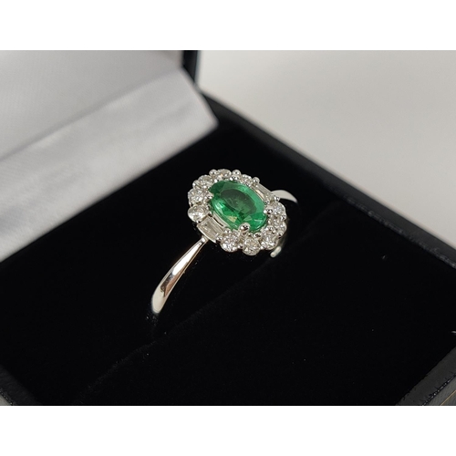 36 - AN 18CT WHITE GOLD EMERALD AND DIAMOND RING, the central oval cut emerald of approximately 0.45 cara... 