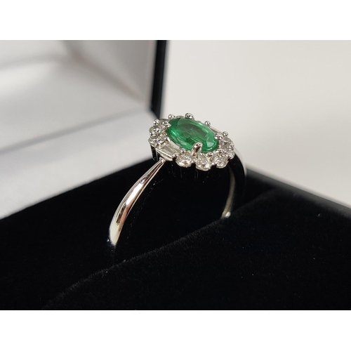 36 - AN 18CT WHITE GOLD EMERALD AND DIAMOND RING, the central oval cut emerald of approximately 0.45 cara... 