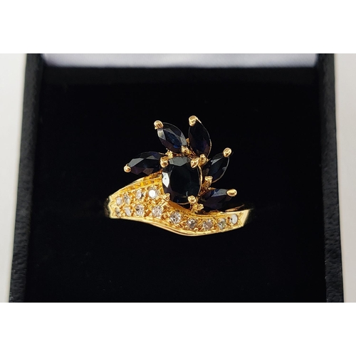 18 - A YELLOW METAL SAPPHIRE AND DIAMOND SET DRESS RING, probably 18ct gold, asymmetrical floral spray wi... 