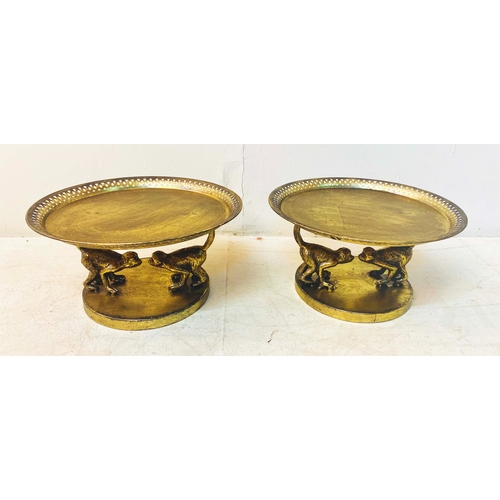 356 - TAZZAS, a pair, gilt finish on monkey supports, 20cm H x 35cm W x 35cm D. (2)