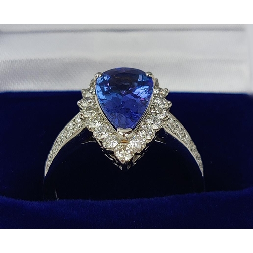 11 - AN 18CT WHITE GOLD TANZANITE AND DIAMOND SET DRESS RING, the single pear shaped mixed cut stone surr... 