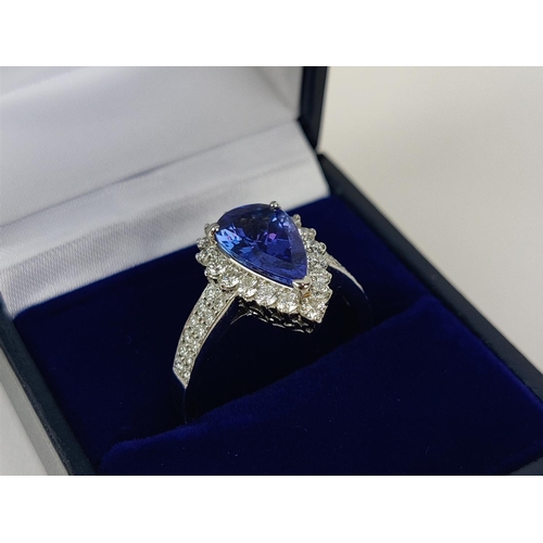 11 - AN 18CT WHITE GOLD TANZANITE AND DIAMOND SET DRESS RING, the single pear shaped mixed cut stone surr... 