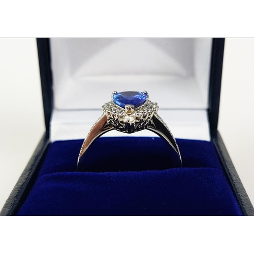 11 - AN 18CT WHITE GOLD TANZANITE AND DIAMOND SET DRESS RING, the single pear shaped mixed cut stone surr... 