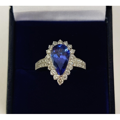 11 - AN 18CT WHITE GOLD TANZANITE AND DIAMOND SET DRESS RING, the single pear shaped mixed cut stone surr... 