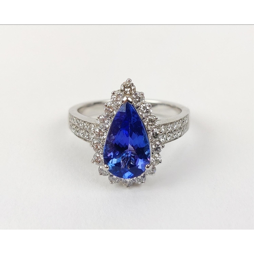 11 - AN 18CT WHITE GOLD TANZANITE AND DIAMOND SET DRESS RING, the single pear shaped mixed cut stone surr... 