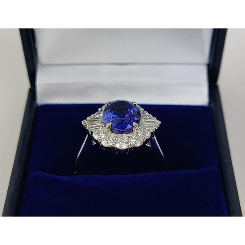 12 - AN 18CT WHITE GOLD TANZANITE AND DIAMOND DRESS RING, the central tanzanite stone surrounded by brill... 