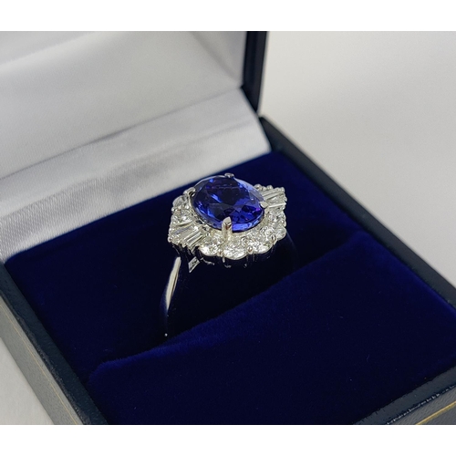 12 - AN 18CT WHITE GOLD TANZANITE AND DIAMOND DRESS RING, the central tanzanite stone surrounded by brill... 