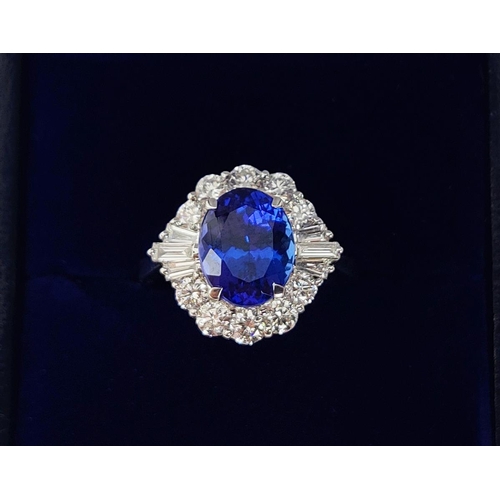 12 - AN 18CT WHITE GOLD TANZANITE AND DIAMOND DRESS RING, the central tanzanite stone surrounded by brill... 