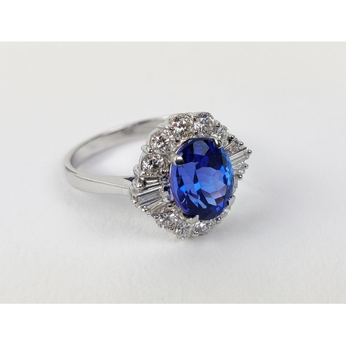 12 - AN 18CT WHITE GOLD TANZANITE AND DIAMOND DRESS RING, the central tanzanite stone surrounded by brill... 