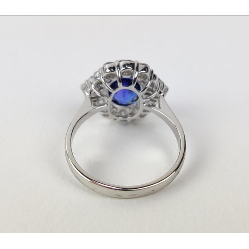 12 - AN 18CT WHITE GOLD TANZANITE AND DIAMOND DRESS RING, the central tanzanite stone surrounded by brill... 