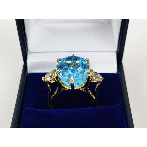 13 - AN 18CT YELLOW GOLD BLUE TOPAZ AND DIAMOND DRESS RING, the central mixed cut topaz of approximately ... 