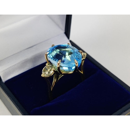 13 - AN 18CT YELLOW GOLD BLUE TOPAZ AND DIAMOND DRESS RING, the central mixed cut topaz of approximately ... 