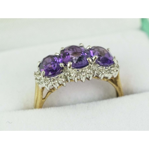 24 - A 9CT YELLOW GOLD AMETHYST THREE STONE TRILOGY RING, having three faceted amethysts, surrounded by d... 