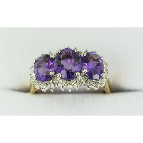 24 - A 9CT YELLOW GOLD AMETHYST THREE STONE TRILOGY RING, having three faceted amethysts, surrounded by d... 